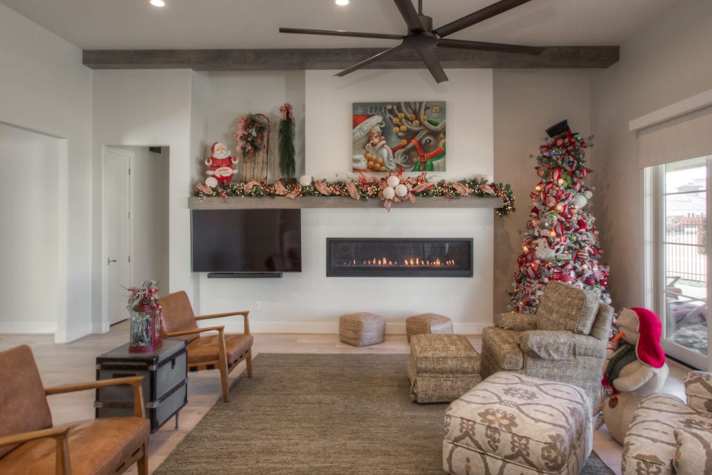 A living room area with a TV, a fireplace, and a holiday tree